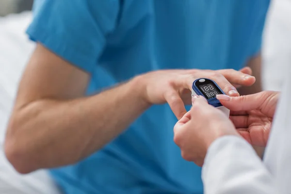 Vista recortada del médico colocando oxímetro de pulso en el dedo en el paciente en el hospital — Stock Photo