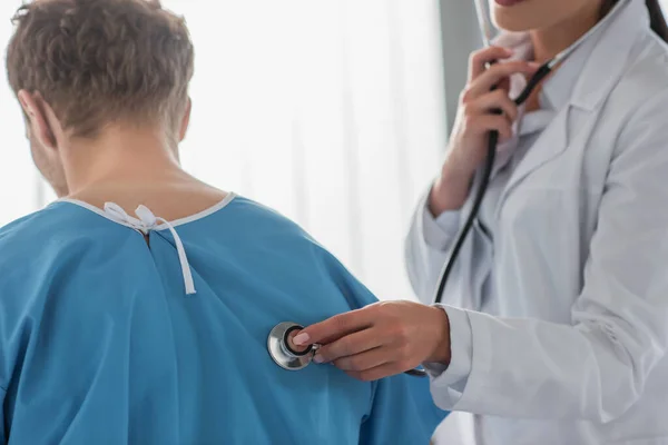 Vista ritagliata del medico che esamina il paziente riccio con stetoscopio — Foto stock