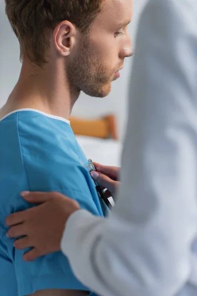 Doctor borroso examinando paciente rizado con estetoscopio - foto de stock