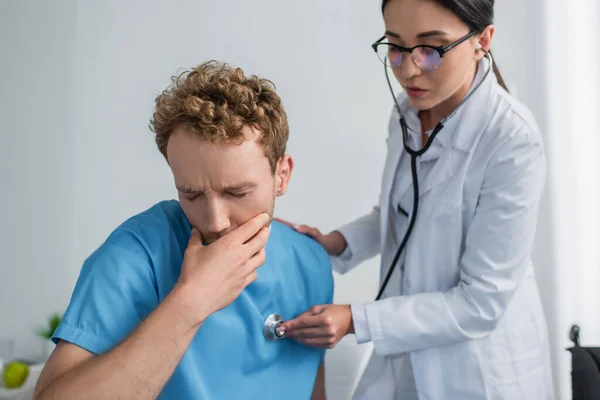 Morena médico en gafas examinar enfermo paciente sofá en el hospital - foto de stock