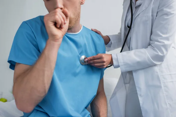 Vista parcial del médico de bata blanca examinando el sofá del paciente enfermo en el hospital - foto de stock