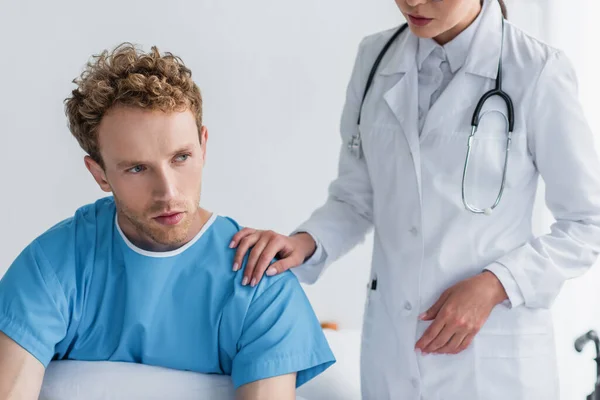 Médico de bata blanca calmando enfermo y frustrado paciente en el hospital - foto de stock