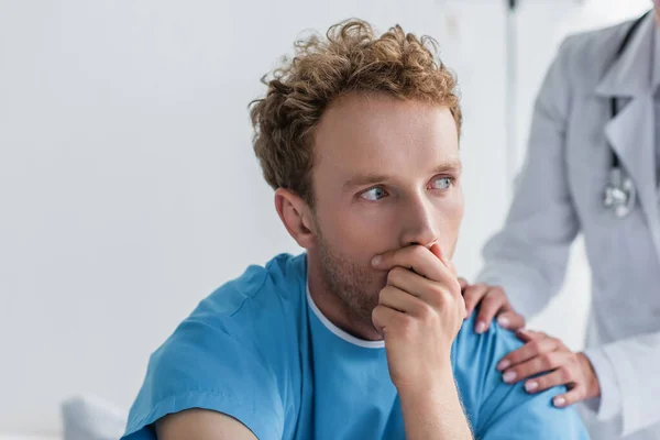 Doctor in white coat calming sick and scared patient in hospital — Stock Photo