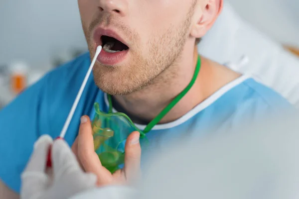 Cropped view of doctor holding swab near patient with open mouth — Stock Photo
