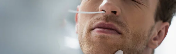 Vista cortada do médico segurando cotonete perto do nariz do paciente enquanto faz o teste de pcr, banner — Fotografia de Stock