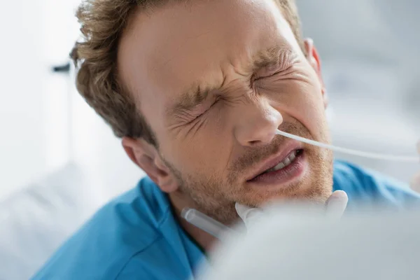 Médecin en gant de latex tenant écouvillonnage près du nez du patient bouclé avec les yeux fermés tout en faisant le test pcr — Photo de stock