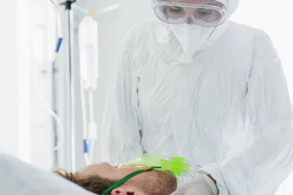 Arzt in persönlicher Schutzausrüstung untersucht Patient in Sauerstoffmaske im Krankenhaus — Stockfoto
