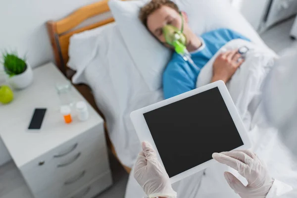 Visão de alto ângulo do médico em luvas de látex segurando comprimido digital com tela em branco perto paciente doente — Fotografia de Stock