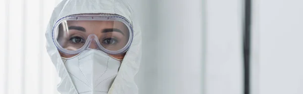Doctor in personal protective equipment and goggles looking at camera, banner — Stock Photo