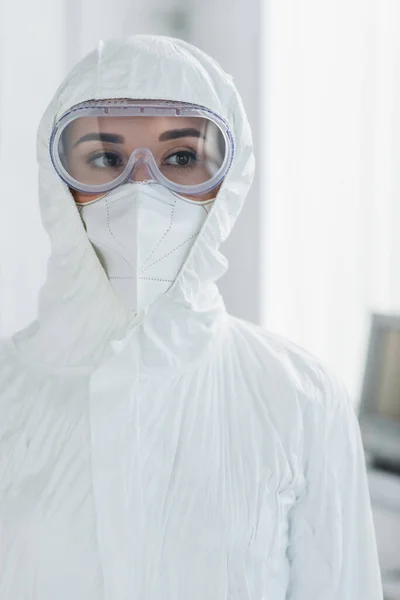 Médico em equipamentos de proteção individual e óculos olhando para longe — Fotografia de Stock