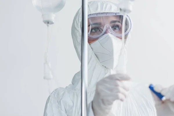 Doctor in personal protective equipment and goggles looking at drop counter — Stock Photo