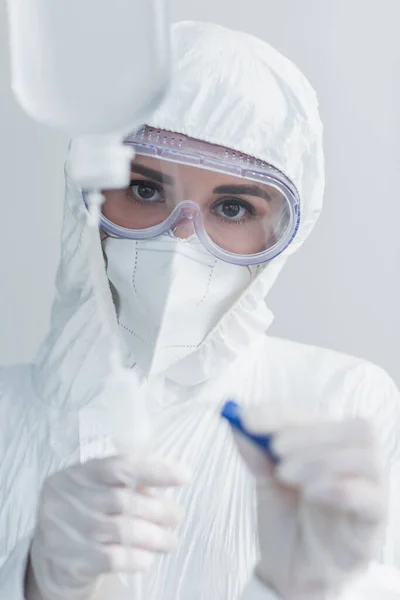 Médecin en combinaison Hazmat et lunettes tenant le cathéter sur le comptoir de goutte — Photo de stock