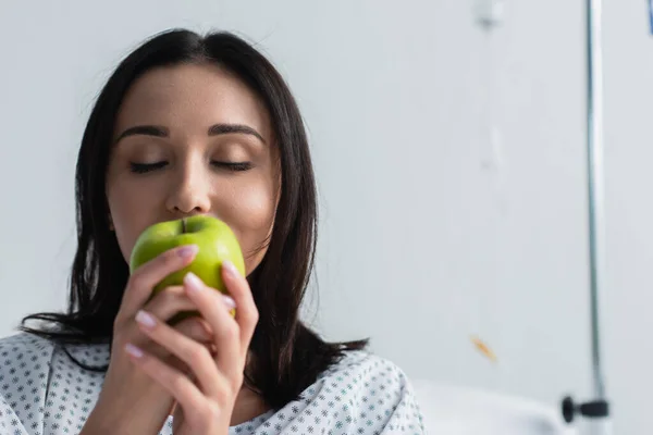 Morena mujer con los ojos cerrados sosteniendo manzana fresca en las manos - foto de stock