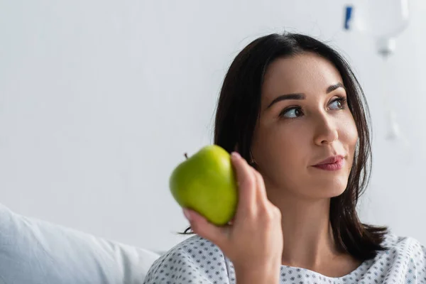 Брюнетка держит свежее яблоко в больнице — стоковое фото