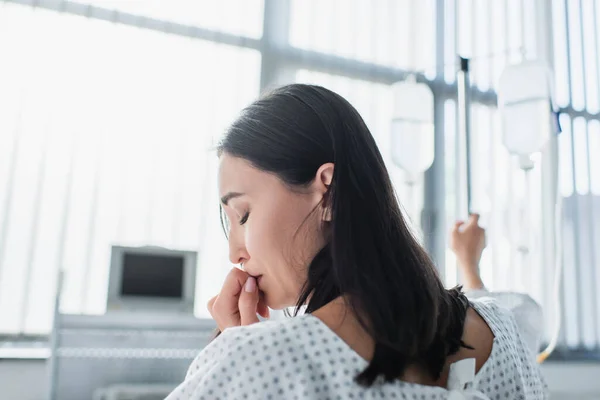 Sick woman with closed eyes feeling pain during therapy in hospital — Stock Photo