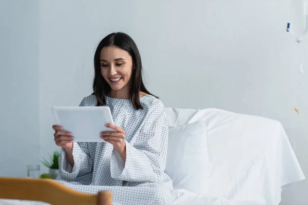 Mujer alegre usando tableta digital en el hospital - foto de stock