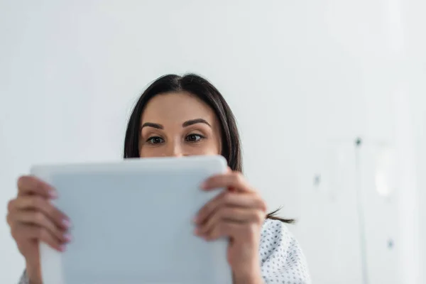 Brünette Patientin verdeckt Gesicht, während sie digitales Tablet im Krankenhaus benutzt — Stockfoto