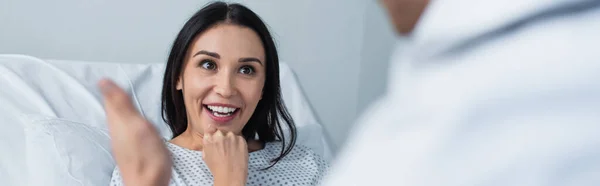 Morena paciente sonriendo mientras mira borrosa médico, pancarta - foto de stock