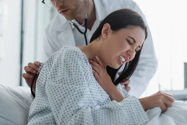 Médico com estetoscópio examinando mulher com dor no peito — Fotografia de Stock