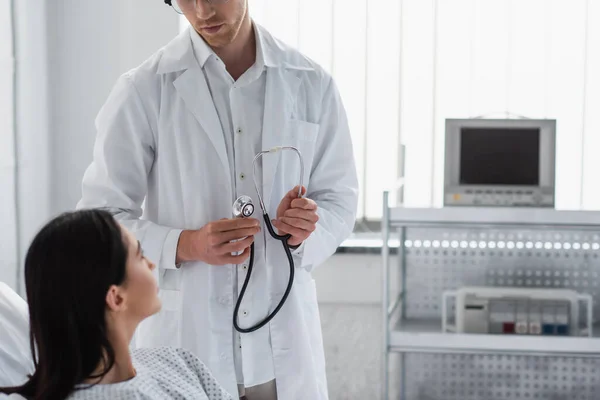 Doctor with stethoscope looking at blurred woman in clinic — Stock Photo