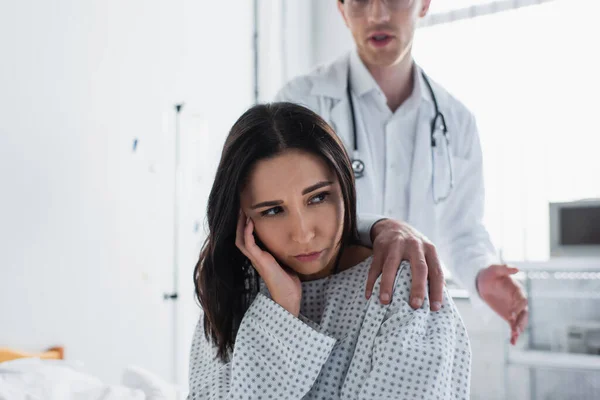 Розмитий лікар торкається плеча засмученого пацієнта — стокове фото