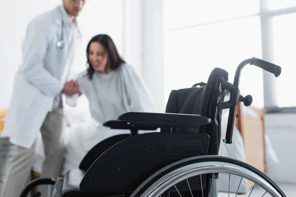 Modern wheelchair near doctor with patient on blurred background — Stock Photo