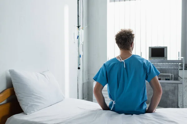 Vista posteriore di uomo riccio seduto sul letto d'ospedale — Foto stock