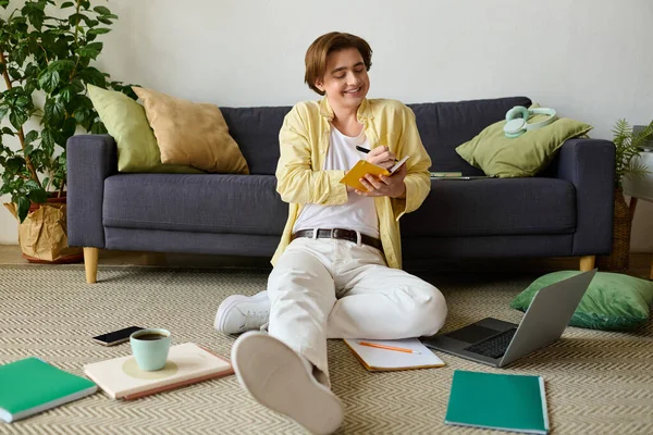 Giovane gioioso in abito casual gode di scrivere note in un ambiente accogliente soggiorno — Foto stock