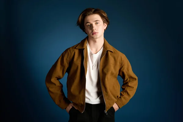 Молодой модный мужчина элегантно позирует, демонстрируя расслабленный и модный наряд в студии. — стоковое фото