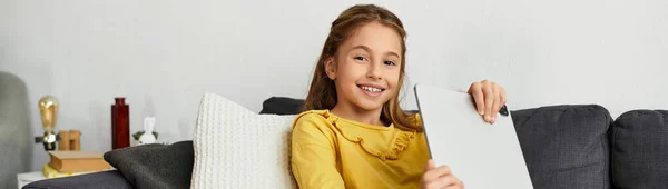 Eine Generation Alpha-Mädchen entspannt auf der Couch, beschäftigt mit ihrem Tablet, lächelt glücklich in ihrem Haus, Transparent — Stockfoto