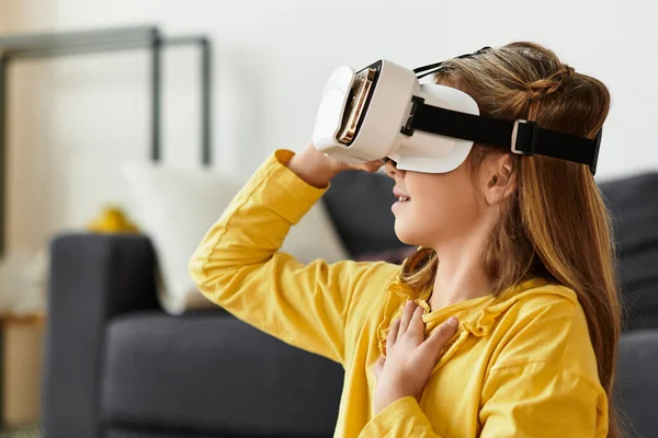 Uma menina desfruta de seu tempo em casa, vestindo uma roupa casual enquanto usa um fone de ouvido de realidade virtual. — Fotografia de Stock