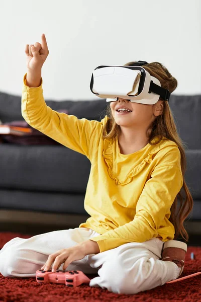 Junges Mädchen genießt eine virtuelle Erfahrung, während sie auf einem weichen Teppich in ihrem gemütlichen Wohnzimmer sitzt. — Stockfoto