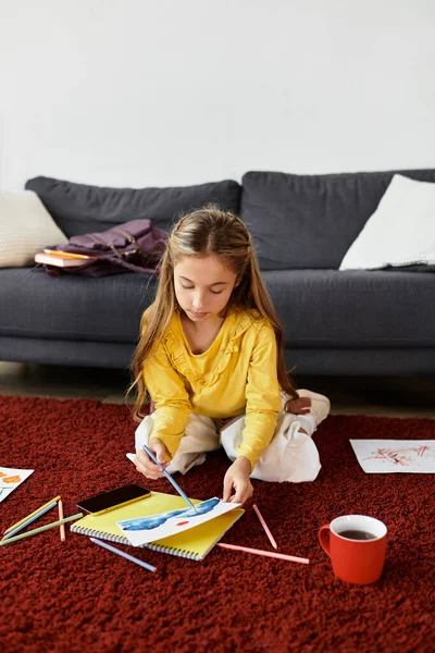Ein Mädchen sitzt auf dem roten Teppich, eingetaucht in Zeichnung und Kreativität mit farbenfrohen Kunstwerken. — Stockfoto