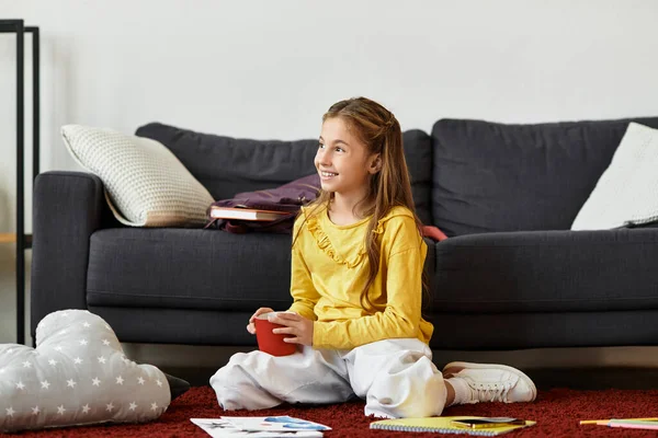 Un niño alfa de generación se sienta cómodamente en una alfombra, participando en un juego creativo con suministros de arte cerca. - foto de stock