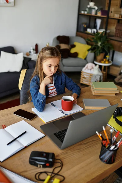 Дівчина досліджує свої думки, розслабляючись вдома з теплим напоєм і ноутбуком. — стокове фото