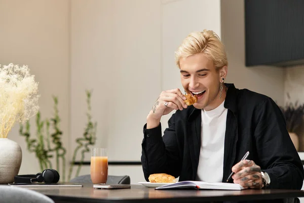 Красивый молодой человек наслаждается завтраком, сидя за современным столом в своей квартире. — стоковое фото