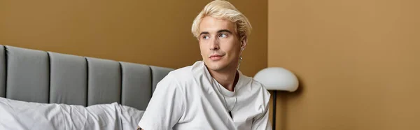 Atractivo joven se relaja en un apartamento elegante, abrazando un momento de calma y estilo. - foto de stock