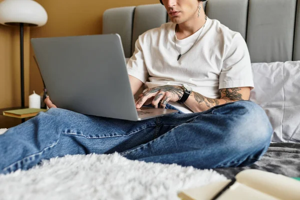 A young man sits on his bed, focused on his laptop, enjoying a peaceful moment. — Stock Photo