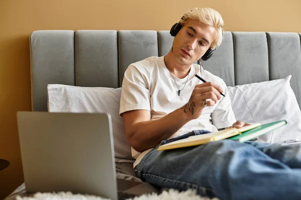 Focalisé individu aime la musique tout en écrivant des notes dans un cadre confortable appartement. — Photo de stock