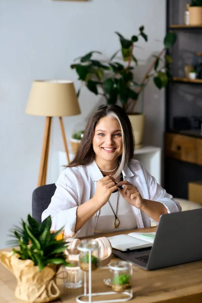 Жінка з синдромом Варденбурга працює з дому, посміхається і займається. — стокове фото