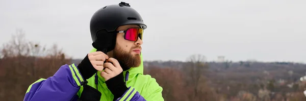 A bearded man confidently adjusting snowboarding helmet, embracing winter sport, banner — Stock Photo