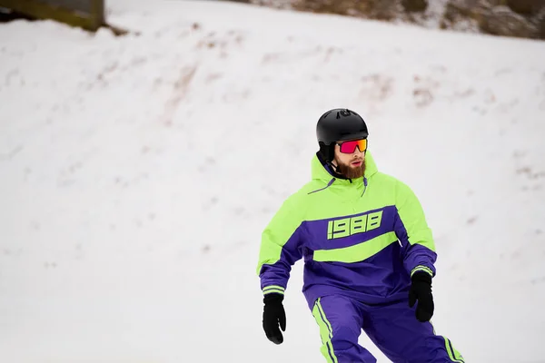 Ein bärtiger Mann brettert gekonnt einen verschneiten Hang hinunter und genießt den Wintersport. — Stockfoto