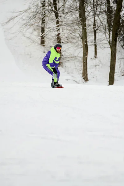 A bearded man skillfully snowboards down a snowy slope in winter, showcasing his active spirit. — Stock Photo