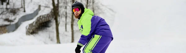 Un homme avec une barbe met en valeur ses compétences en snowboard sur une pente enneigée en tenue d'hiver, bannière — Photo de stock