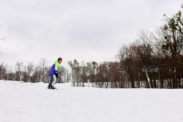 Un barbudo disfruta del snowboard por una ladera nevada, rodeado de árboles de invierno. - foto de stock