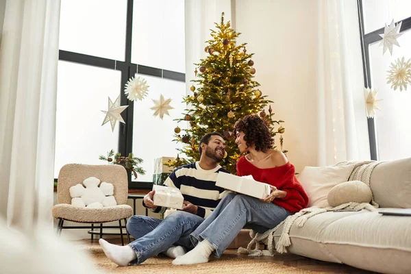 Ein fröhliches Paar teilt besondere Momente gemeinsam an einem schön geschmückten Weihnachtsbaum. — Stockfoto