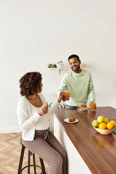 Una coppia gioiosa si gode spuntini e bevande a casa mentre celebra la loro gravidanza insieme. — Foto stock