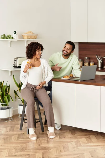 Una coppia felice condivide un momento leggero nella loro cucina mentre si preparano per un nuovo bambino. — Foto stock