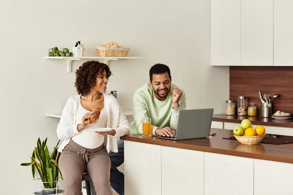 Счастливая пара наслаждается качеством времени в своей уютной кухне во время подготовки к их новому прибытию. — стоковое фото