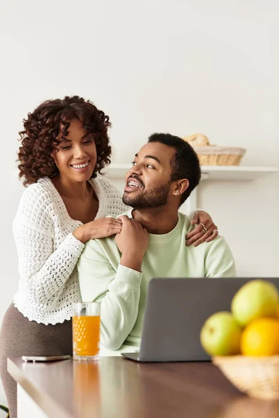 Счастливая пара наслаждается временем вместе, работая над ноутбуком в своем стильном доме. — стоковое фото